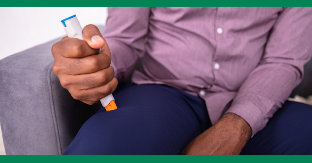 Close-up of a person using an epinephrine auto-injector on their thigh